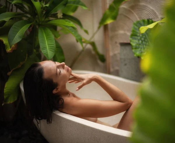Donna rilassante nel bagno all'aperto con foglie tropicali a Bali — Foto Stock