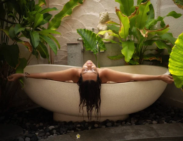 Mulher relaxante em banho ao ar livre com folhas tropicais em Bali — Fotografia de Stock