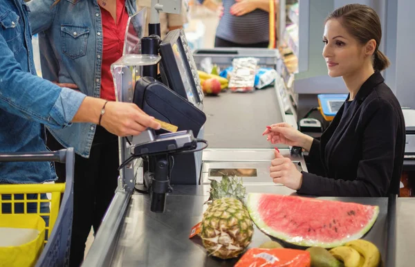 Pareja comprando bienes en una tienda de comestibles — Foto de Stock