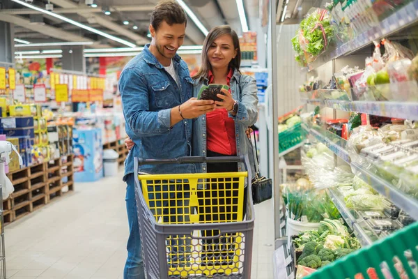 Pareja eligiendo mercancías en una tienda de comestibles — Foto de Stock