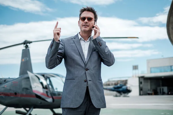 Uomo d'affari che parla al telefono vicino all'elicottero privato — Foto Stock