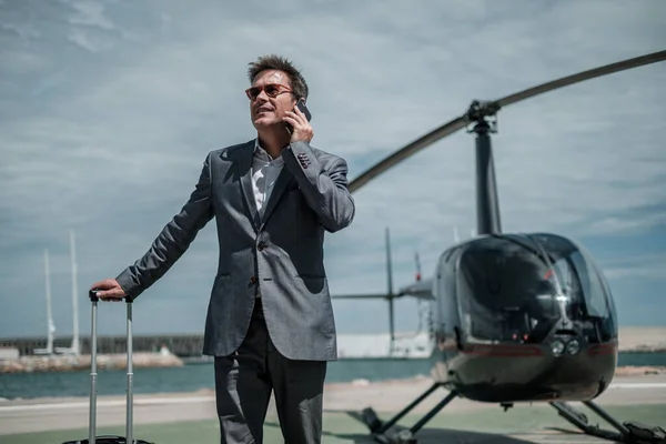 Бізнесмен розмовляє по телефону біля приватного вертольота — стокове фото