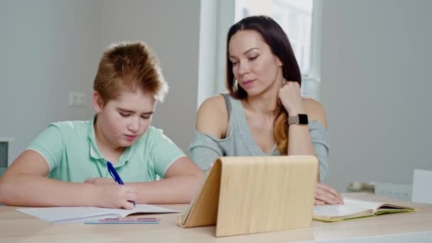 Mère avec son fils étudiant en ligne à la maison — Video