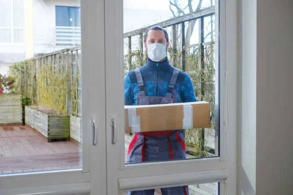 Corriere protetto con maschera e guanti consegna pacco ad un cliente — Foto Stock