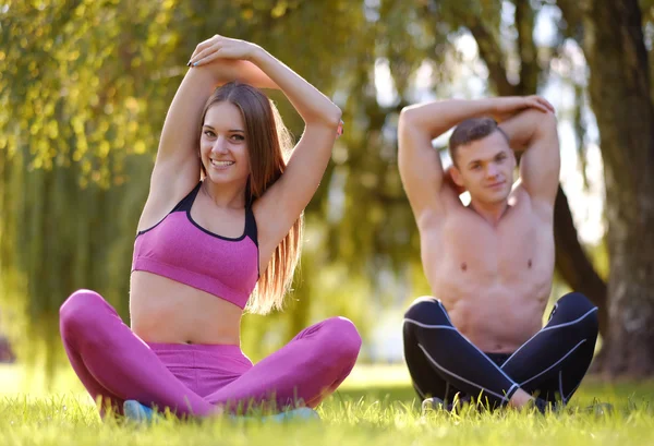 Couple relaxing on a grass after yoga exercises — Stock Photo, Image