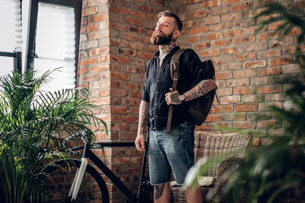 Bebaarde hipster houdt Lederen rugzak — Stockfoto