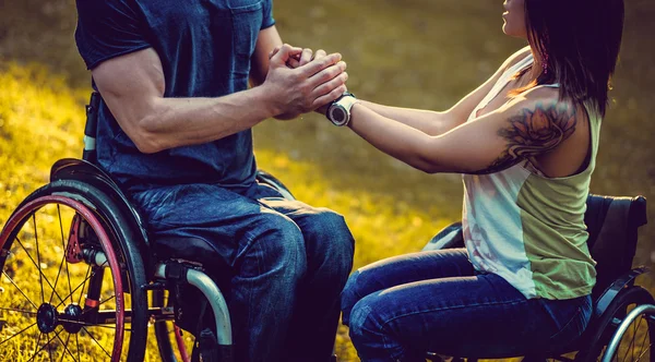 Homme en fauteuil roulant tient les bras d'une femme handicapée — Photo