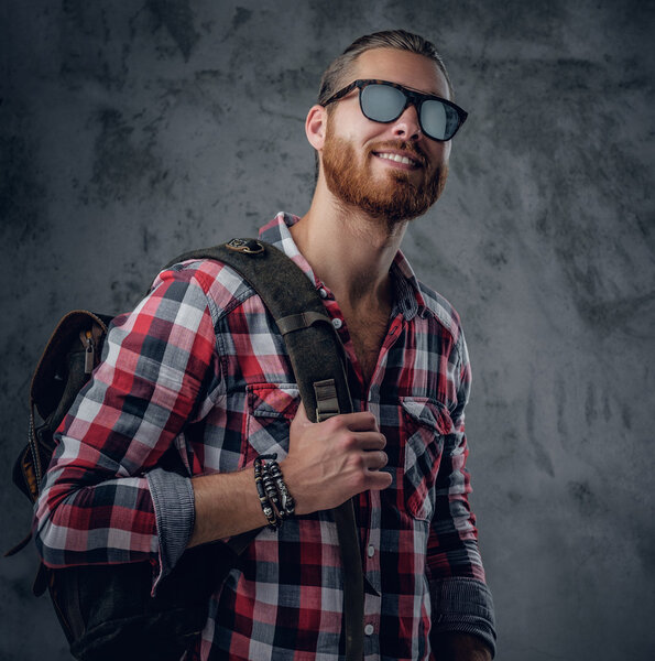 Urban traveller in sunglasses holds backpack