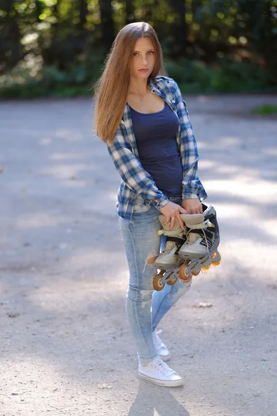 Langhaarige Frau hält Rollschuh. — Stockfoto