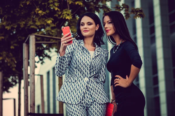 Two fashionable women using smartphone — Stock Photo, Image