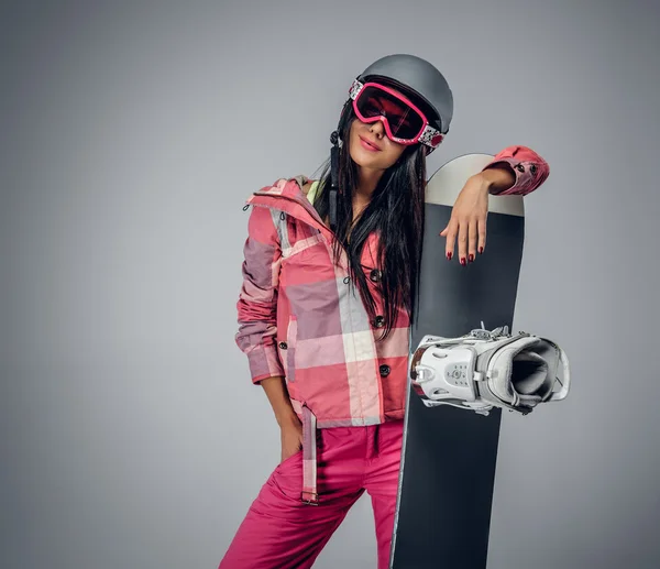 Жінка в рожевому лижному костюмі, що тримає сноуборд — стокове фото