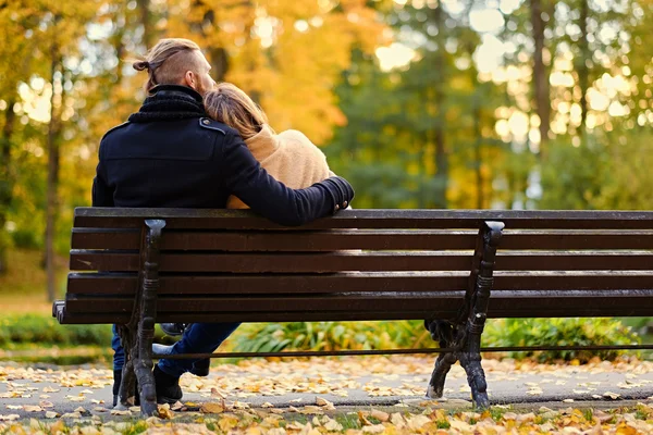 Casal sentado no banco no parque de outono — Fotografia de Stock