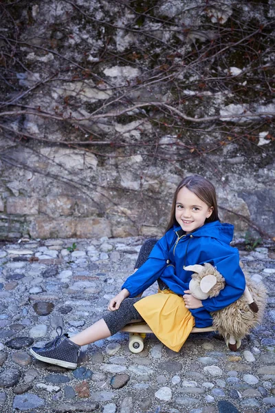 Ładna dziewczynka siedzi na deskorolce — Zdjęcie stockowe
