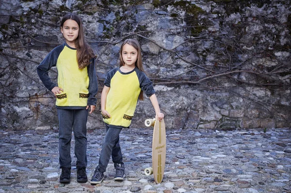 Dziewczyny w żółty ubrania gospodarstwa deskorolka — Zdjęcie stockowe