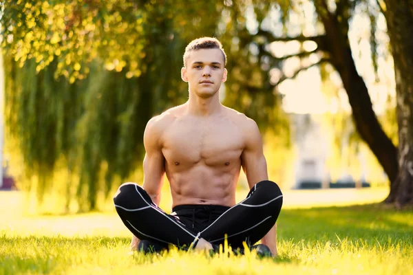 El macho abdominal sin camisa se sienta en una hierba — Foto de Stock