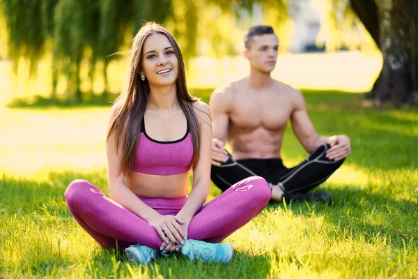 Giovane coppia sportiva rilassante su un'erba — Foto Stock