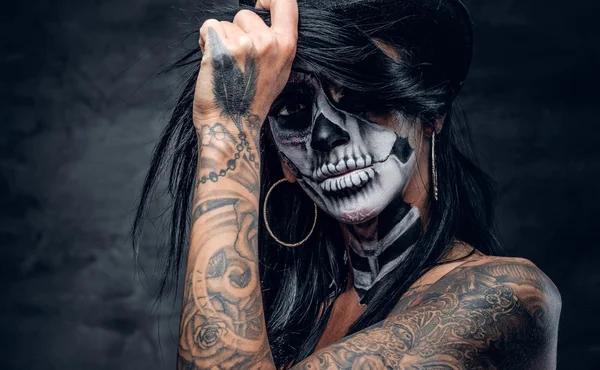Девушка с макияжем черепа и татуированной рукой — стоковое фото