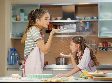 Two girls having fun in the kitchen clipart