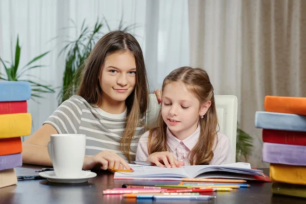 女の子がたくさんの本とのテーブルで勉強して. — ストック写真