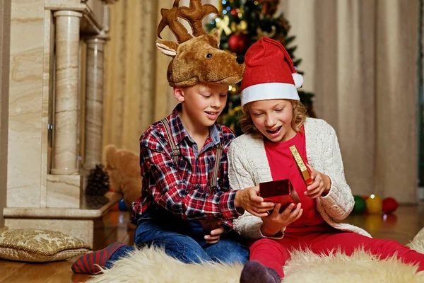 Мальчик в рождественской шляпе и девочка держит подарок — стоковое фото