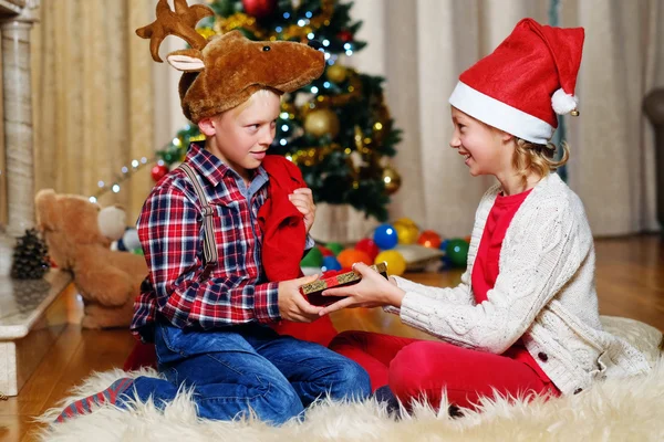 Boy in Christmas hat and girl holds gift