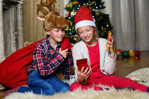 Boy in Christmas hat and girl holds gift