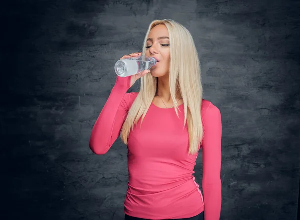 Blonde vrouw drinken van een fles water. — Stockfoto