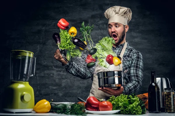 Zaskoczony mężczyzna kucharz z latające warzywa — Zdjęcie stockowe
