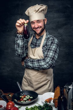 Gülümseyen aşçı erkek patlıcan tutar.