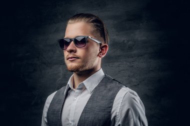 Güneş gözlüklü bir adam kolsuz gömlek giymiş.