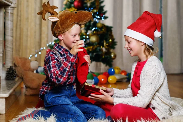 Мальчик в рождественской шляпе и девочка с подарком — стоковое фото