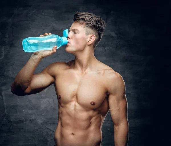 Shirtless muscular male drinking water