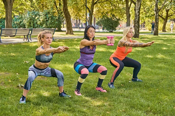 Tres mujeres deportistas haciendo sentadillas — Foto de Stock