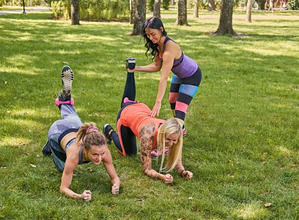 Sporty girl teaching two women legs workout