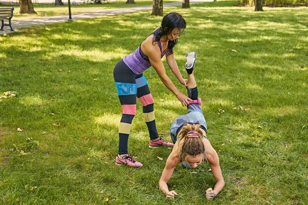 Entrenador enseñando a una mujer piernas entrenamiento —  Fotos de Stock