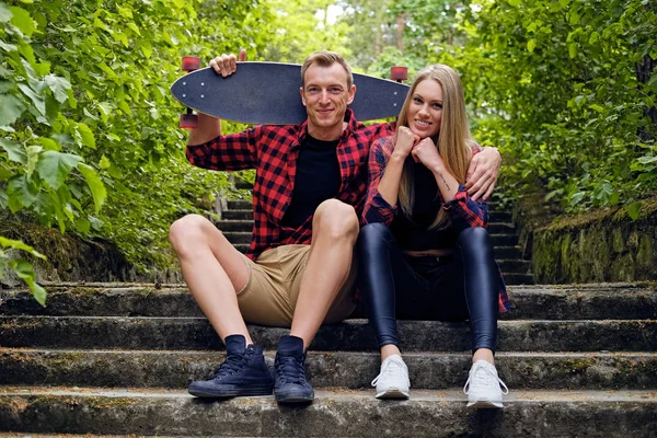 Paar entspannt sich nach Longboard-Fahrt auf den Stufen. — Stockfoto