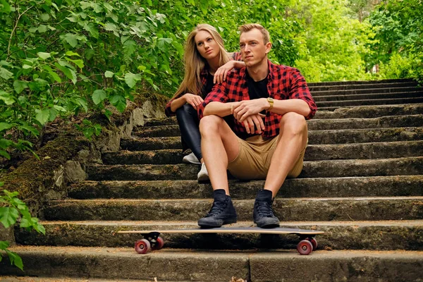 Paar ontspannen op de stappen na longboard rit. — Stockfoto
