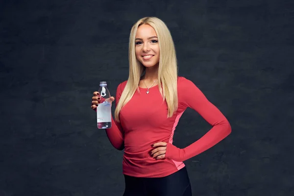 Sportliche blonde Frau trinkt Wasser. — Stockfoto