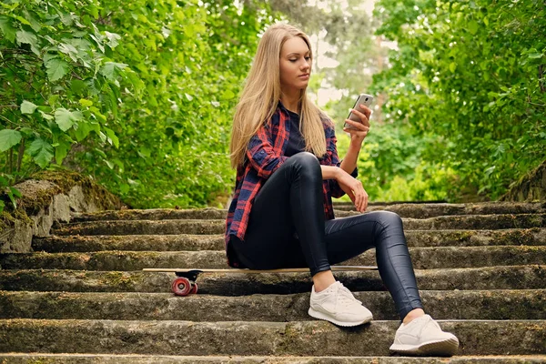 Meisje met behulp van een smartphone en zit op de stappen. — Stockfoto