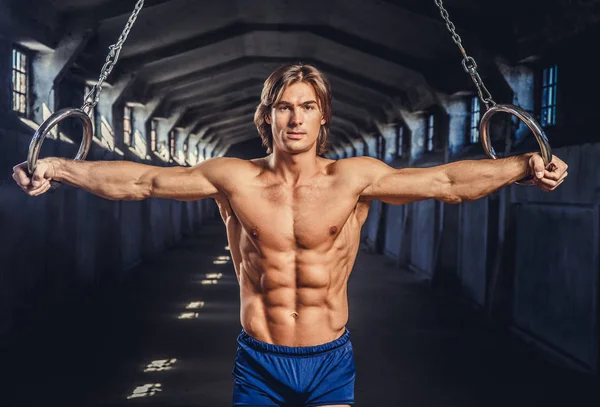Muskulöser Mann posiert mit Turnringen — Stockfoto