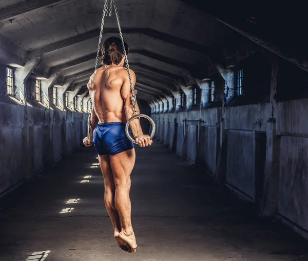 Homem muscular posando com anéis de ginástica — Fotografia de Stock