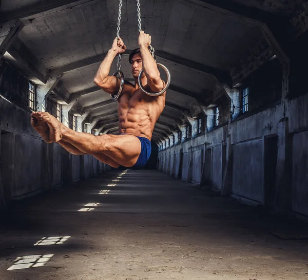 Homem muscular posando com anéis de ginástica — Fotografia de Stock