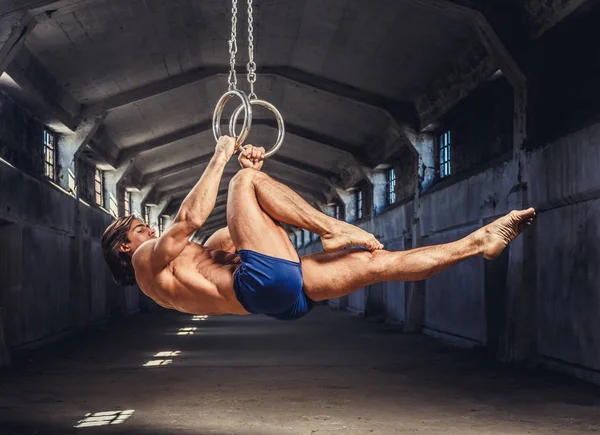 Muskulös man poserar med Gymnastringar — Stockfoto