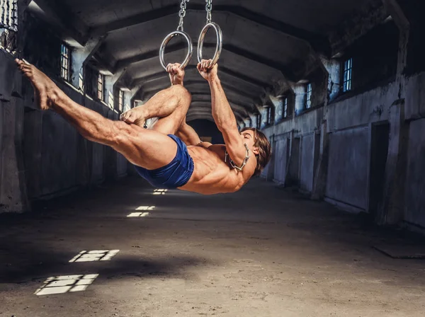 Homme musculaire posant avec des anneaux de gymnastique — Photo