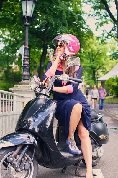 Frau im Kleid sitzt auf einem Motorroller — Stockfoto
