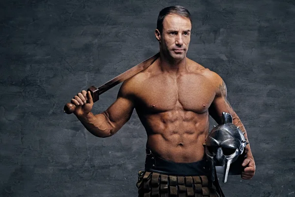 Muscular man holding helmet and sword — Stock Photo, Image