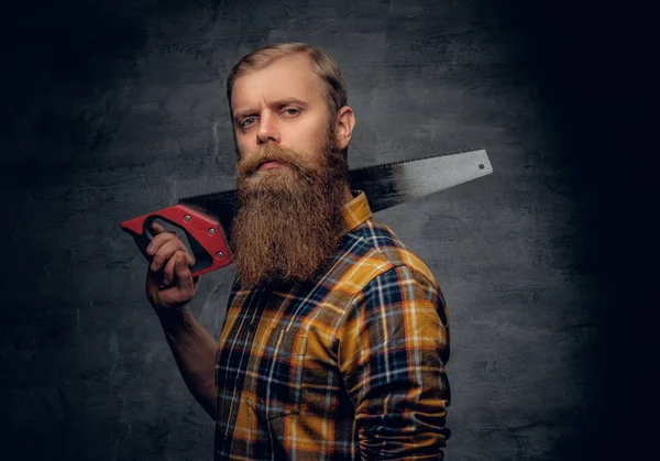 Homem de carpinteiro barbudo segurando serra manual . — Fotografia de Stock