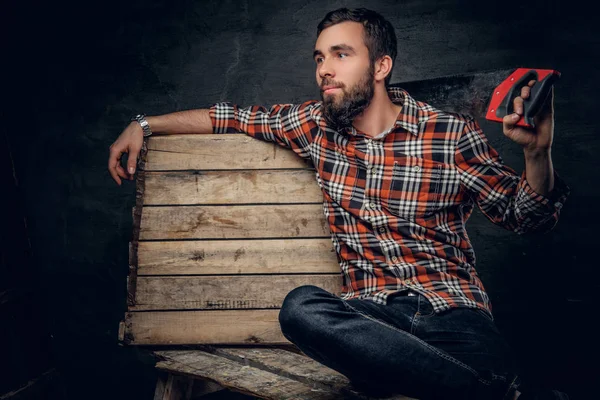 Vousatý carpenter drží pilkou — Stock fotografie