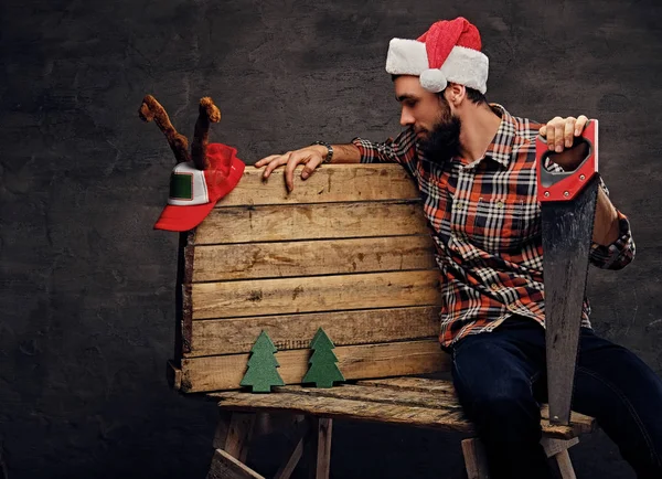 Hombre en el sombrero de Santa sosteniendo la sierra — Foto de Stock
