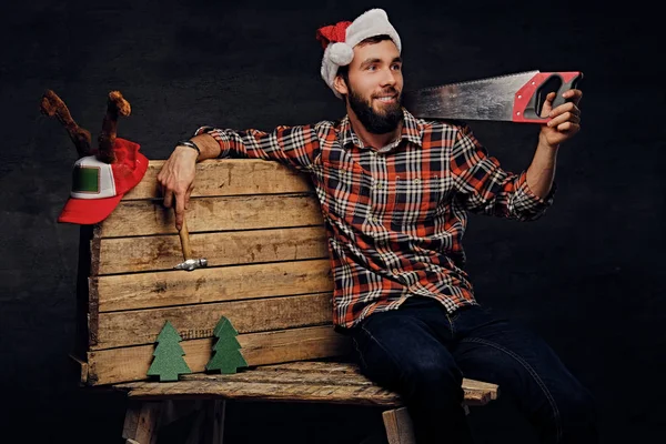 Mann mit Weihnachtsmannmütze und Handsäge — Stockfoto